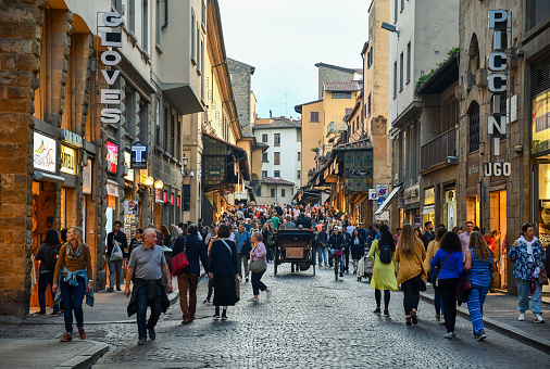 Florence, Tuscany / Italy - October 18 2019: View of the Ponte Vecchio bridge in the historic centre with people and tourists walking late in the afternoon