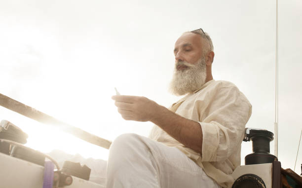 IQOS. Bearded man vape on yacht. Senior Vaping, Enjoying An Electronic Cigarette. IQOS. Bearded man vape on yacht. iqos e cig stock pictures, royalty-free photos & images