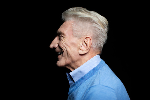 Profile view of senior man smiling on black background. Caucasian mature man looking happy against black background.