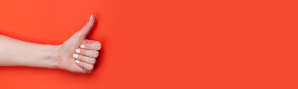 istock close-up female hand shows thumb up on red background 1196405105