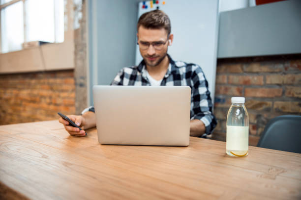 istock Smiling young guy holding smartphone in hand 1196409208