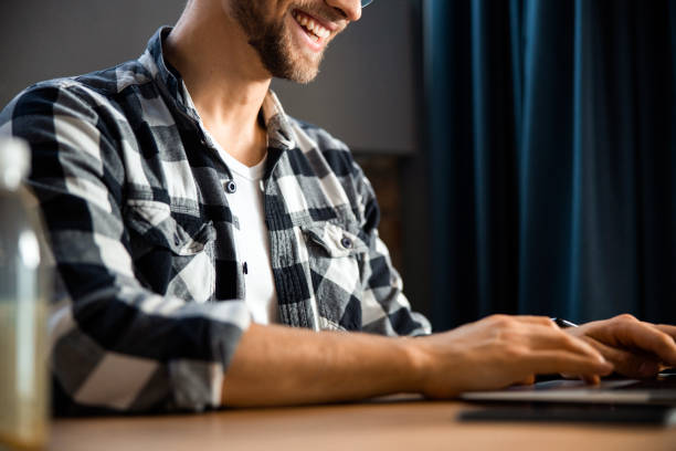 istock Happy young man sitting and typing on laptop 1196409213