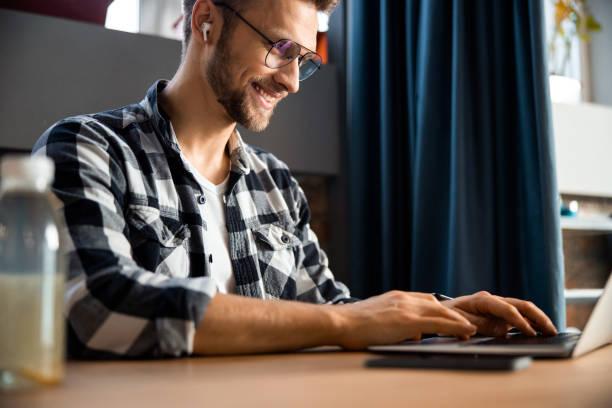 istock Smiling handsome guy with laptop at cafe 1196409216