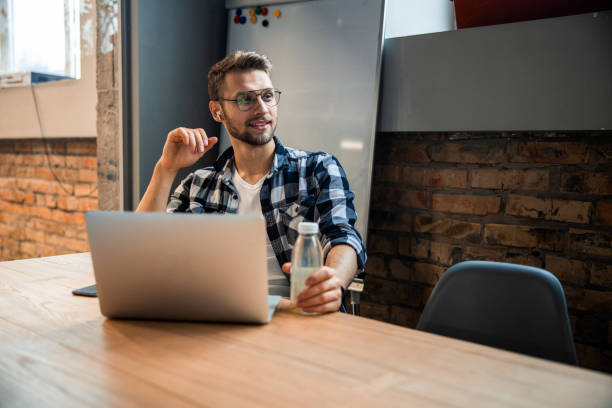 istock Smiling young man is using headphones in the office 1196409262