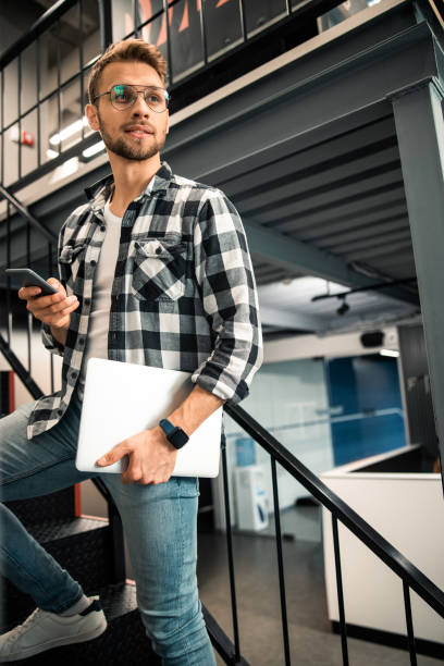 istock Young man is holding smartphone and laptop 1196409269