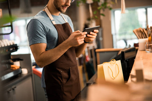 istock Smiling barista holding a tablet computer in a coffee shop 1196410125