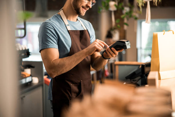 istock Happy male waiter in apron with card reader 1196410127