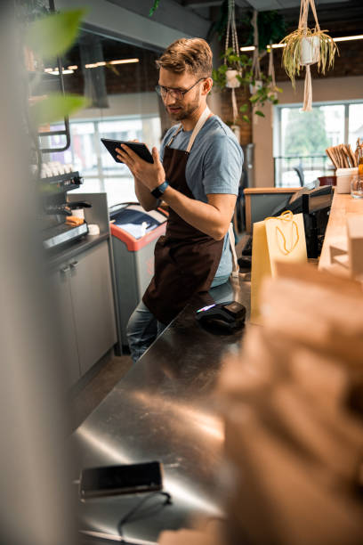 istock Happy male owner of cafe using digital tablet 1196410143