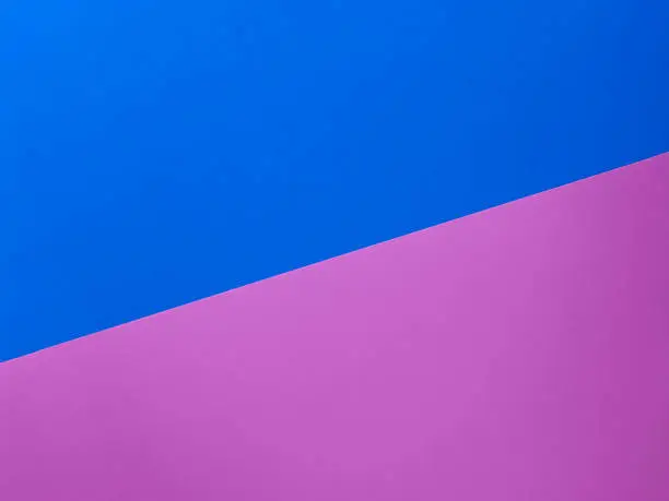 Two trendy colored papers arranged in diagonal top view. Pink and blue paper texture abstract background with copy space for your design. Can be used for greeting cards, banners.