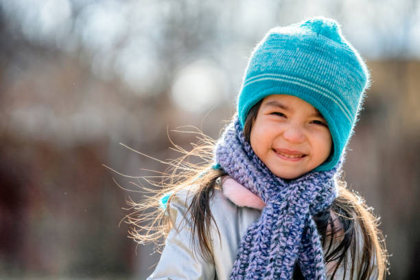 belle fille de course mélangée de trois ans souriant et jouant dans son arrière-cour rectifiée vers le haut chaudement pour l'amusement d'hiver - warmly photos et images de collection