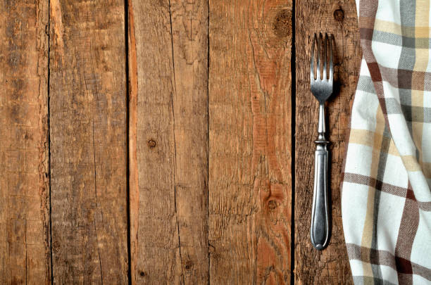istock Checkered tablecloth right frame and fork on vintage wooden table background - view from above 1196417460