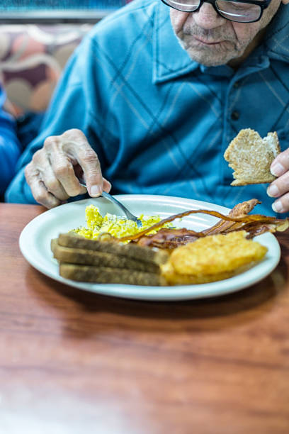 istock Elderly Arthritic Man Eating Breakfast in Restaurant 1196423693