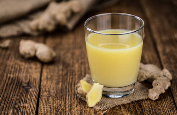 alter holztisch mit frischem ingwersaft (nahaufnahme; selektiver fokus) - schnapsglas stock-fotos und bilder