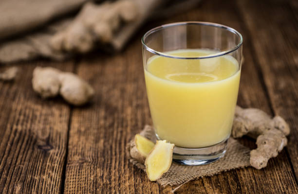 Old wooden table with fresh Ginger Juice (close-up shot; selective focus) Healthy Ginger Sap on a wooden table as detailed close-up shot (selective focus) ginger spice stock pictures, royalty-free photos & images
