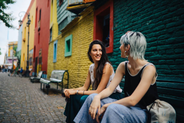 Girls sitting in front of a vintage house Two young women sitting in front of a colorful vintage house and talking, Buenos Aires, Argentina. la boca buenos aires stock pictures, royalty-free photos & images