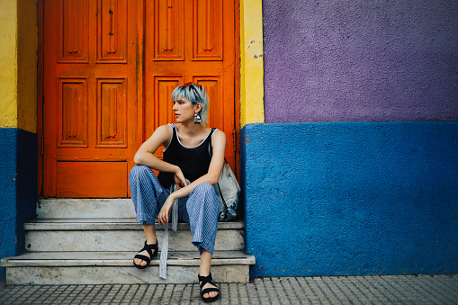 Young pretty woman sitting on the doorstep of a vintage house in Buenos Aires, Argentina.