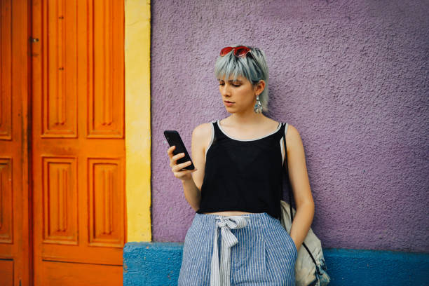istock Trendy girl using phone outdoors 1196431168