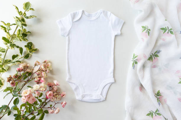 Blank White Baby Grow On An Off White Background With Pink Roses and baby muslin - Spring Baby Bodysuit Mockup - Styled Stock Photo Baby Clothing Mockup to add own designs to babygro stock pictures, royalty-free photos & images