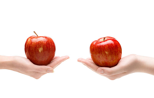 istock Two hands each offering the other a shiny red apple 119643560