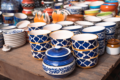 Rows and shelves of various colorful ceramic jars and bowls and cups for sale at a market in New Delhi India