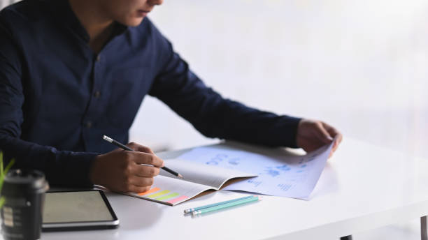 istock Cropped shot businessman writing conclusion his paper work and notebook. 1196442316