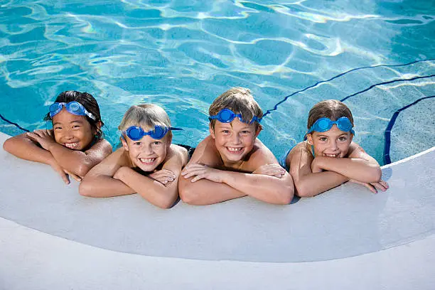 Photo of Children smiling at edge of swimming pool