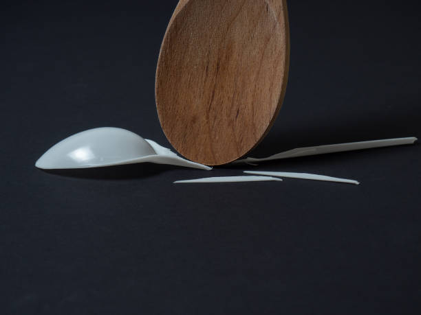 istock Wooden spoon breaks a plastic disposable spoon on a black background. Close up view. Without plastic concept 1196449224