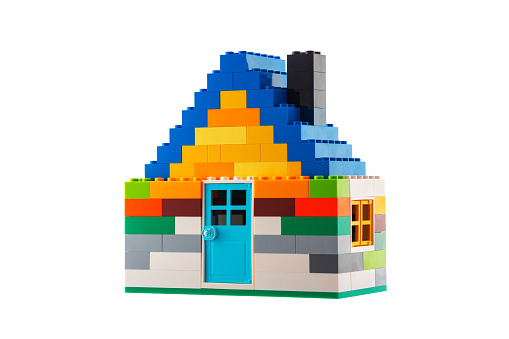 House made of classic building blocks, white studio background.