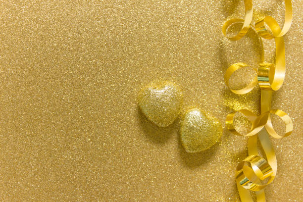 istock Two golden hearts on golden glitter background 1196476321