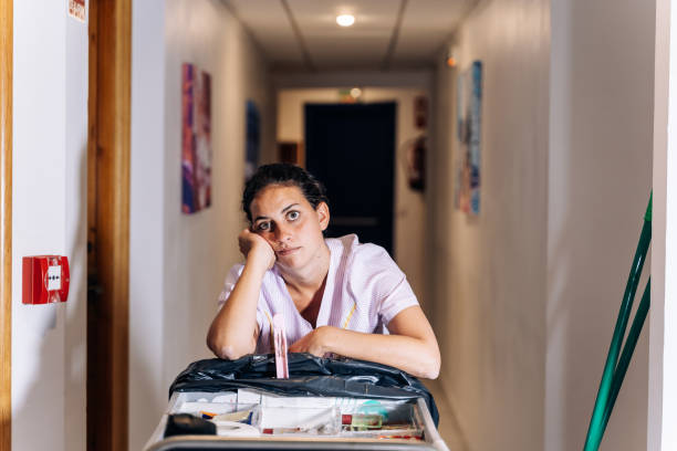 Hotel cleaner leaning on the material trolley to clean in a passageway stock photo