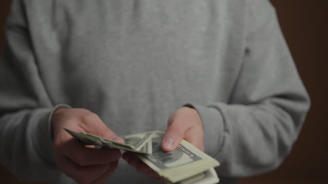 Close up man hands counting cash money at brown wall background