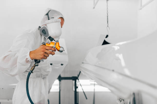 istock Worker in protective workwear painting car parts using spray compressor. 1196485581