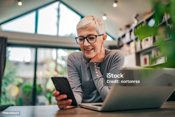 Portrait Of A Cheerful Senior Businesswoman Using Smart Phone At Home Office Closeup Stock Photo - Download Image Now