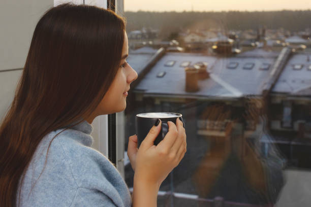 istock Nice girl drinks coffee and looks out the window at sunset 1196491112