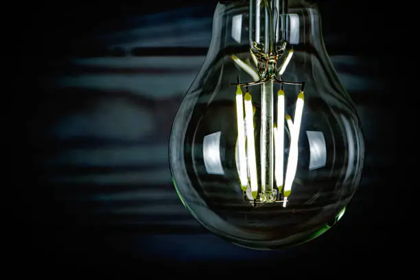 Photo of LED light bulb glowing on wooden background closeup.