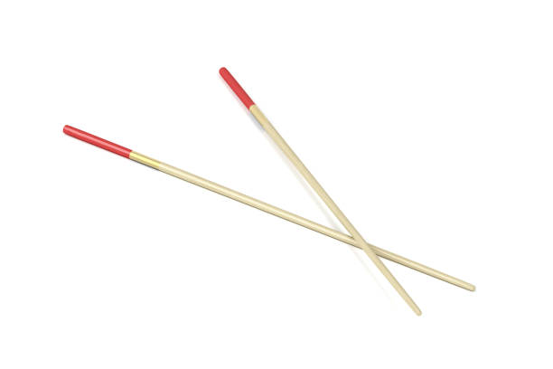 Close-up of chopsticks resting on an empty red spoon. A black background lends elegance and adds a minimalist style to the image.