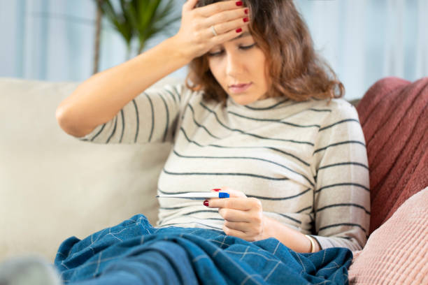 istock Sick woman taking her temperature at home 1196497652