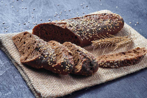 istock Sliced bread with seeds on sackcloth and dark wooden background 1196499697