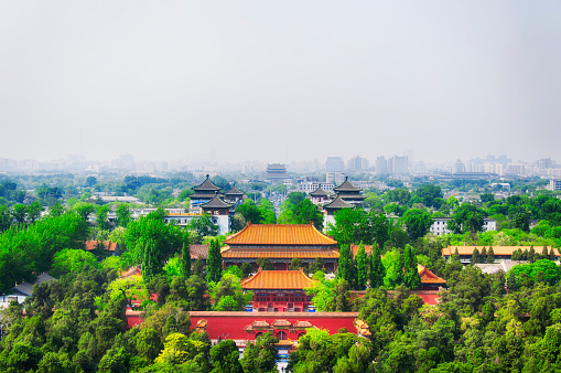 Chinese buildings within Jingshan park located within the city of Beijing China on a hazy day.