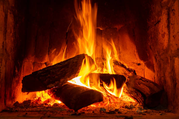 Fire in a fireplace with logs and flames creating a sense of warmth and coziness. Fire in a fireplace with logs and flames creating a sense of warmth and coziness. Keep warm. roaring fireplace stock pictures, royalty-free photos & images