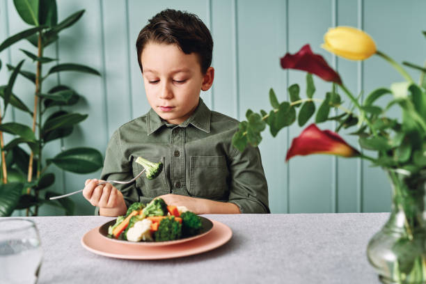 dziecko jest bardzo niezadowolone z konieczności jedzenia warzyw. na jego talerzu jest dużo warzyw. nienawidzi warzyw. - cute disgust carrot caucasian zdjęcia i obrazy z banku zdjęć
