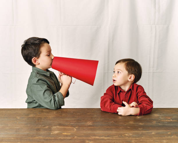 istock Two children are talking with paper megaphone 1196505046