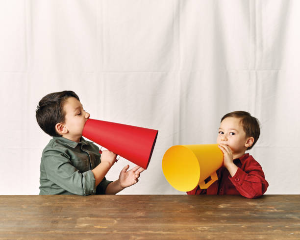 istock Two children are talking with paper megaphone 1196505101