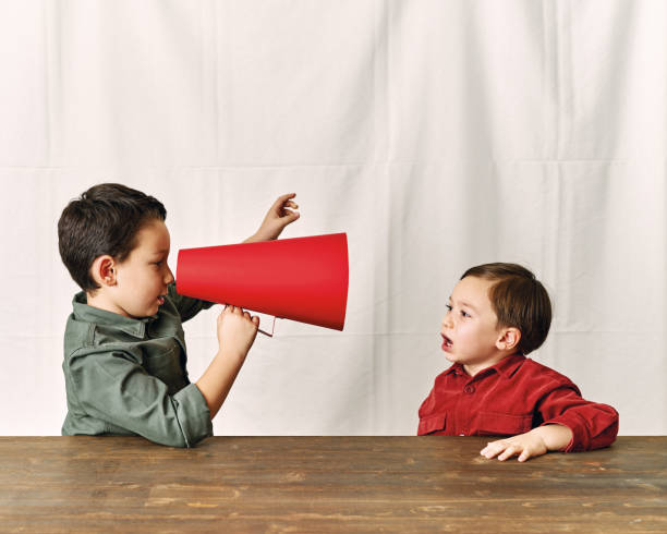 istock Two children are talking with paper megaphone 1196505109