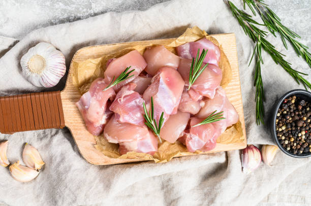 chicken thigh fillet cut into cubes. gray background. top view - chicken thighs imagens e fotografias de stock