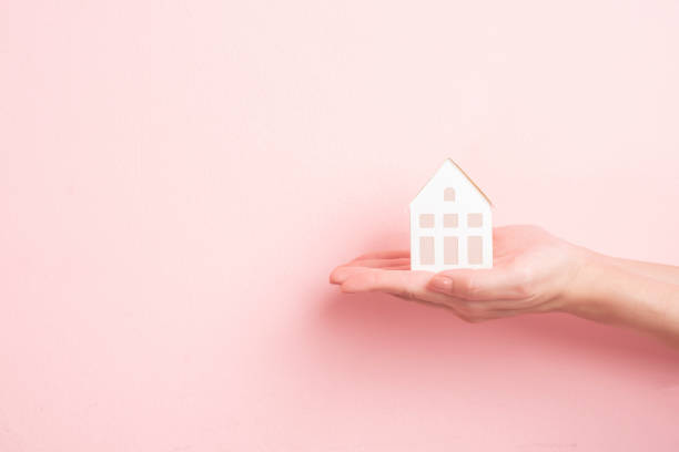 istock Small white house on human hand 1196505893