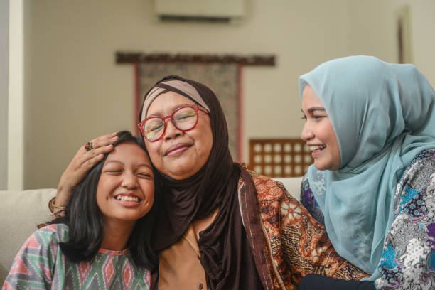 potret bahagia gadis muda muslim asia bersama ibu dan nenek yang duduk di rumah saat perayaan hari raya - budaya indonesia foto potret stok, foto, & gambar bebas royalti