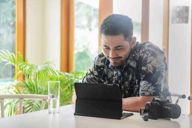 istock Shot of a handsome Asian young man using a tablet at home with camera 1196506894