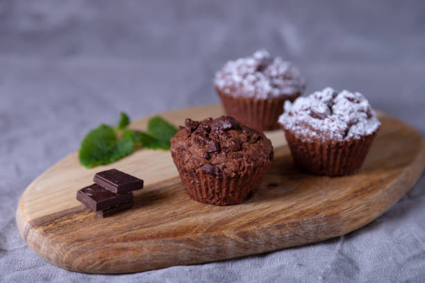 istock Chocolate muffins with mint on a wooden board, sprinkled with powdered sugar. 1196509787