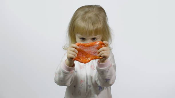 istock Kid playing with hand made toy slime. Child having fun making orange slime 1196510264